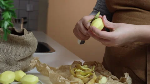 Close-up of woman's hands peeling potatoes in the kitchen Stock Footage 311931999