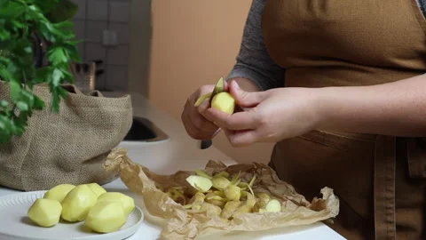 Close-up of woman's hands peeling potatoes in the kitchen  Stock Footage 311932051