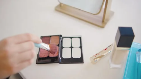 Close-up of a woman's hands picking up blush with a makeup brush from a palette Stock Footage 284036788