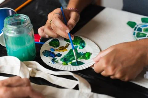 Close-up of a woman's hands picking up paint from a color palette with a Stock Photos