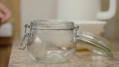 Close-up of a woman's hands pouring melted butter into a glass jar. Stock Footage 128132254