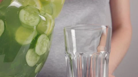Close-up of a woman's hands pouring sassi lemonade from a jug into a glass glass Stock Footage 156549182