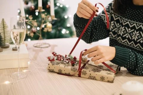Close-up on woman's hands preparing gift with red ribbon Stock Photos