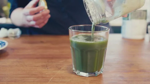 Close up of woman's hands preparing a green barley juice from powder using a jar Stock Footage 273510780