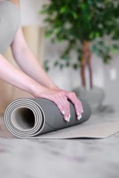 Close-up of a woman's hands preparing a mat for yoga or meditation. Stock Photos