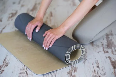 Close-up of a woman's hands preparing a mat for yoga or meditation. Stock Photos