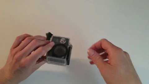 Close-Up Woman's Hands Pushing Button Turning on Sports Camera  in Protective Stock Footage 84999776