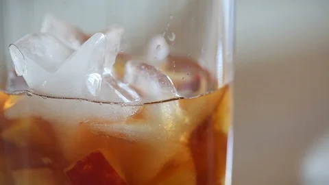 Close-up of the woman`s hands putting ice in a glass with peach tea. Stock Footage 91124719