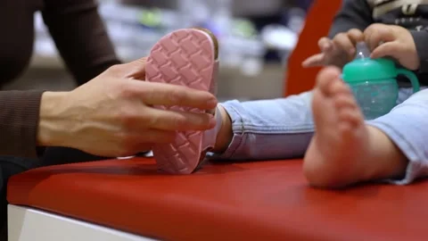Close up of woman's hands putting sandals on little girl's leg Stock Footage 239265633