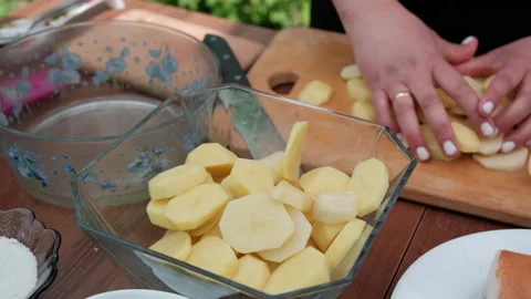 Close-up of a woman's hands putting sliced potatoes on a plate. Stock Footage 194541420