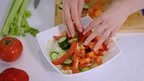 Close-up of a woman's hands putting vegetables into a white salad plate Stock Footage 234701470