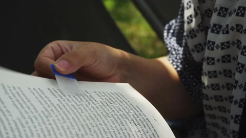 Close-up of a woman's hands reading a book holding a transparent divider in a Video stock 170016929