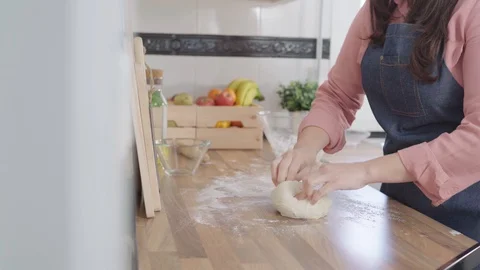 Close up of a Woman's hands rolling the dough on a wooden counter in their ho Stock Footage 128202074