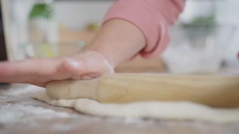 Close up of a Woman's hands rolling the dough on a wooden counter in their ho Stock Footage 128202109