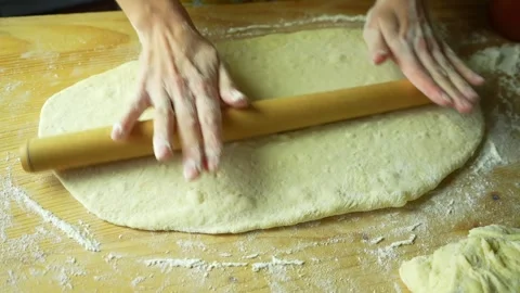 Close-up woman's hands rolling out yeast dough on light brown wooden board. Stock Footage 220227613