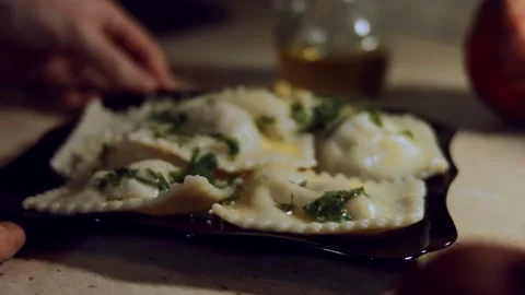 Close-up of woman's hands rotating a plate with hot cooked ravioli covered with Stock Footage 144835391