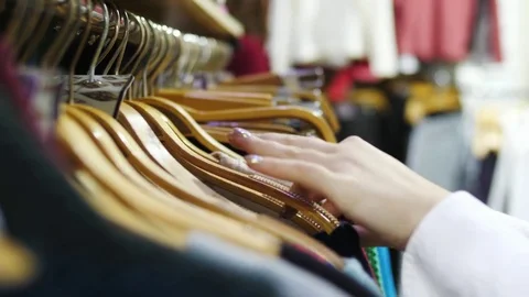 Close-up of woman's hands run across a rack of clothes, browsing in a boutique. Stock Footage 82900211