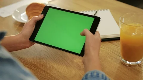 Close-up of woman's hands scrolling down page on tablet with green screen in the Stock Footage 72362303