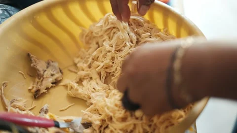 Close up of a woman's hands shredding boiled chicken breast in a yellow bowl Video stock 343435839