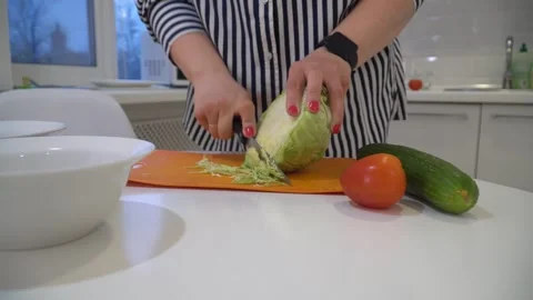 Close-up of a woman's hands slicing cabbage with a knife on a cutting board in t Stock Footage 308870417