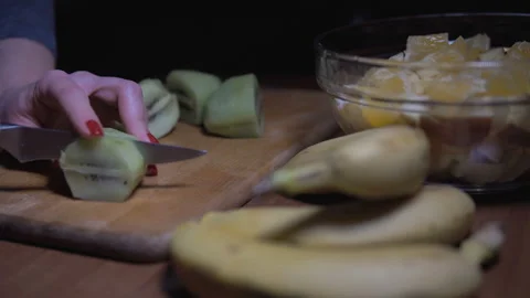 Close-up of woman's hands slicing kiwi on wooden Board. Stock Footage 101204115