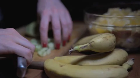 Close-up of woman's hands slicing kiwi on wooden Board. Stock Footage 101204128
