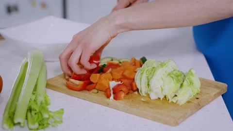 Close-up of a woman's hands slicing vegetables into a salad on a wooden board Stock Footage 234701497