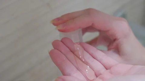A close-up of a woman's hands squeezes liquid transparent onto the arm for Stock Footage 203791108