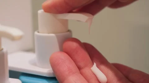 A close-up of a womans hands squeezing soap from a dispenser in a bathroom Stock Footage 334138219