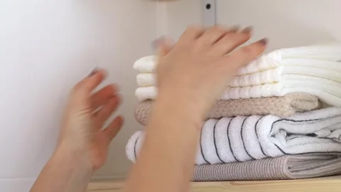 Close-up woman's hands stack clean towels on a shelf. Stock Footage 251518301