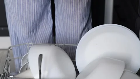 Close-up of a womans hands stacking clean white plates from a dishwasher 動画素材 328979065