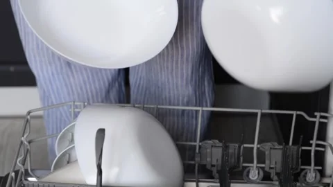 Close-up of a womans hands stacking clean white plates from a dishwasher Vídeo Stock 328979100