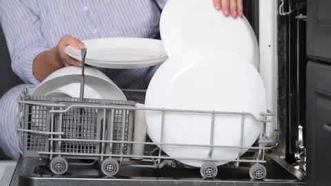 Close-up of a womans hands stacking clean white plates from a dishwasher Vídeo Stock 328979106