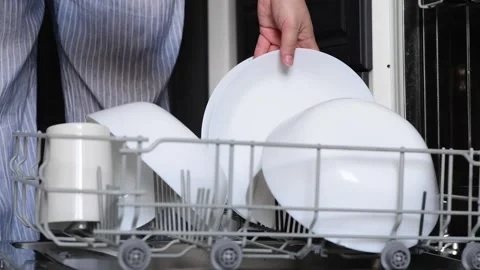 Close-up of a womans hands stacking clean white plates from a dishwasher Vídeo Stock 328979164