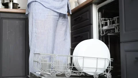 Close-up of a womans hands stacking clean white plates from a dishwasher Vídeo Stock 328985813