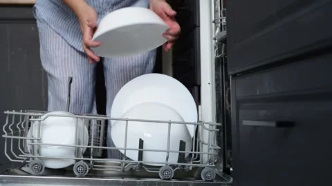 Close-up of a womans hands stacking clean white plates from a dishwasher Stock Footage 328985815
