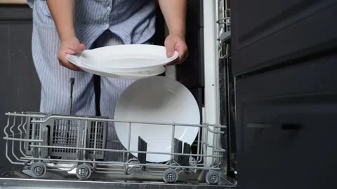 Close-up of a womans hands stacking clean white plates from a dishwasher Vídeo Stock 328985820