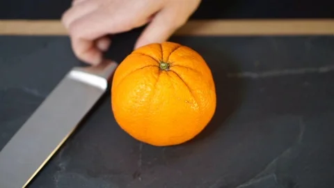 Close up, a woman's hands take a knife and cut the orange exactly in half Stock Footage 106760084