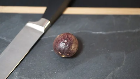 Close up, a woman's hands take a knife and cut the Passion Fruit exactly in half Stock Footage 106760748