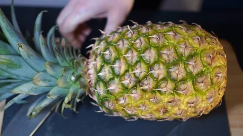 Close up, a woman's hands take a knife and cut the Pineapple exactly in half, Stock Footage 106761075