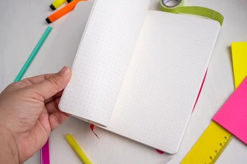 Close up womans hands taking dotted pages of bullet journal planner. Concept for Stock Photos