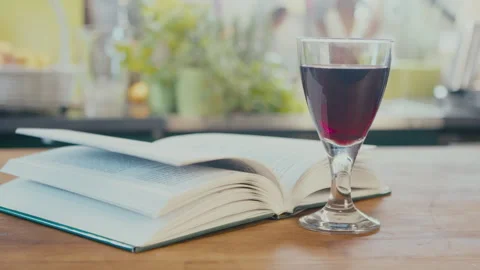 Close up of woman's hands taking eyeglasses and a glass of wine and a book in a Stock Footage 273510980