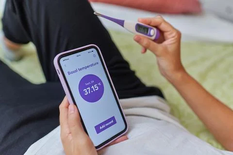 Close up of a woman's hands taking her basal temperature Stock Photos