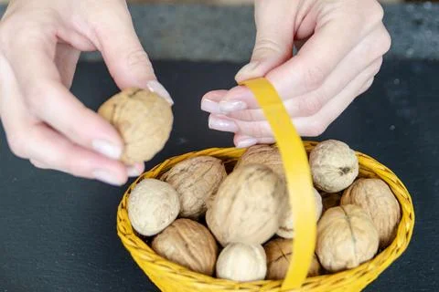 Close-up of a woman's hands taking a walnut from basket. Snack on healthy nuts Foto stock