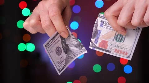 Close-up of a woman's hands tearing 100 hundred dollar paper bill into two parts Stock Footage 262492310
