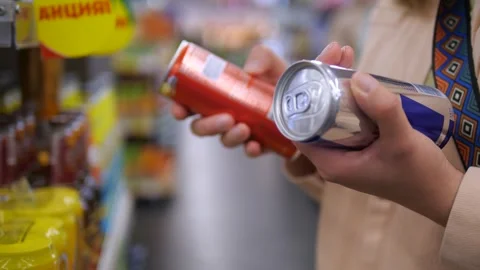 Close-up of a womans hands thoughtfully selecting energy drink cans from a well Vídeo Stock 314822972