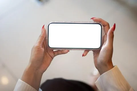 Close up of a woman's hands touching white screen smartphone while sitting .. Stock Photos