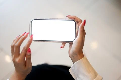 Close up of a woman's hands touching white screen smartphone while sitting .. Stock Photos