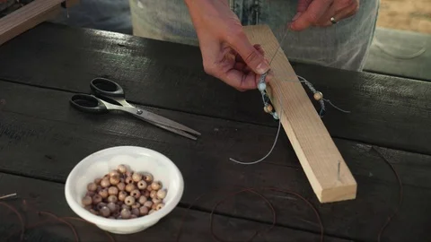 Close-up of a woman's hands tying a knot on a handcrafted bracelet of beads 動画素材 119648419