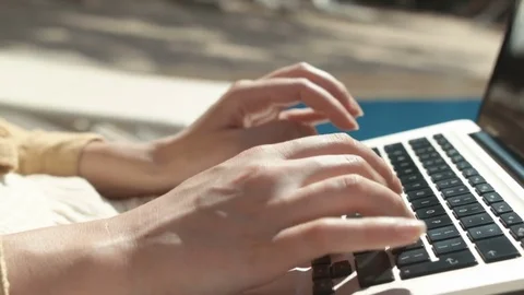 Close up of woman's hands typing on a laptop computer outdoors. Stock Footage 83863523